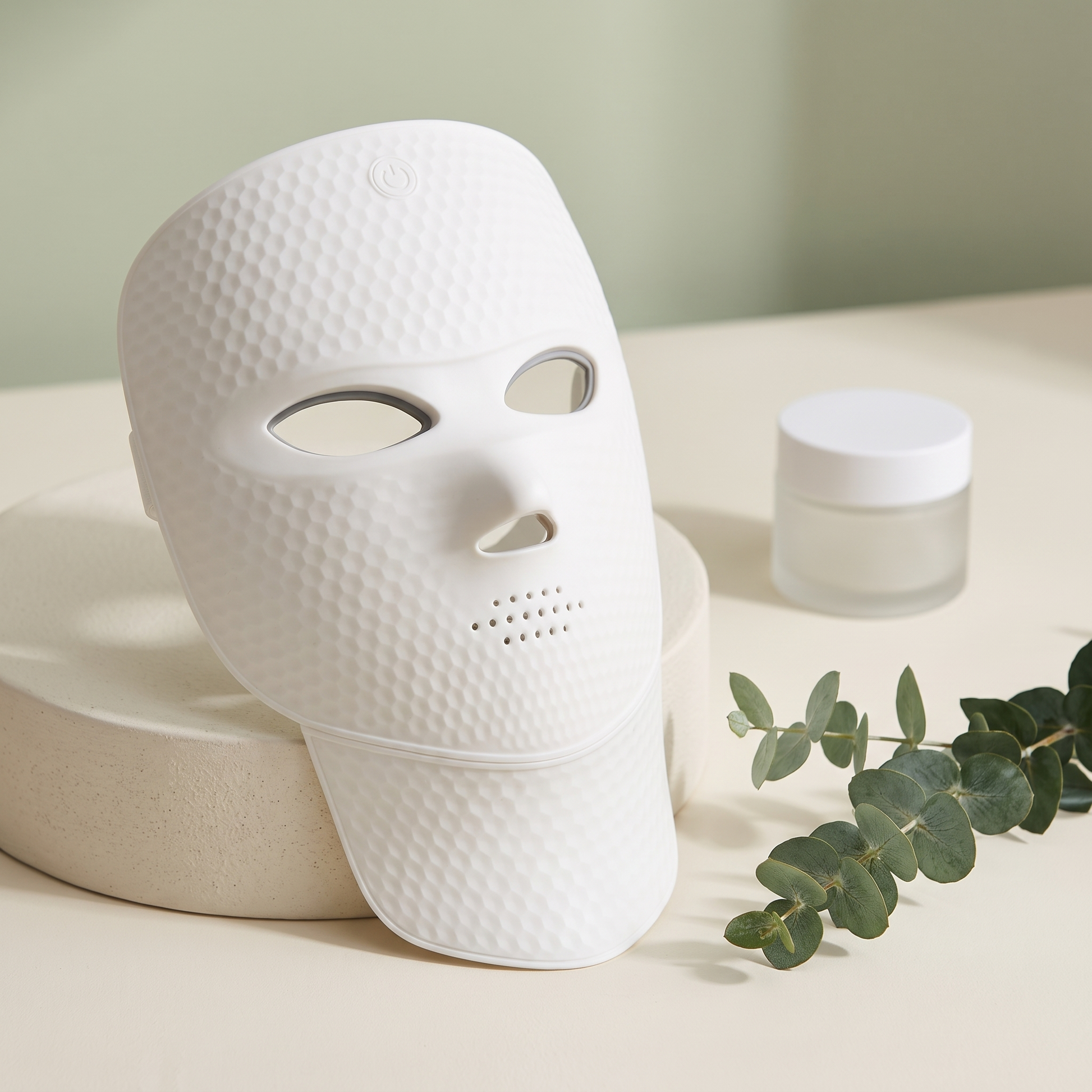 Aurora LED Light Mask on cream surface with eucalyptus