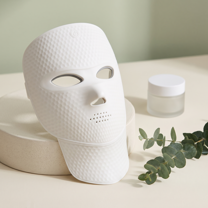 Aurora LED Light Mask on cream surface with eucalyptus